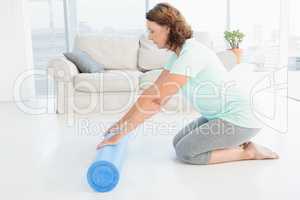 Mature woman rolling exercise mat