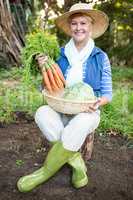 Portrait of happy woman with carrots at garden