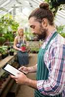 Side view of gardener using digital tablet at greenhouse