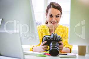Portrait of confident professional with digital camera and compu