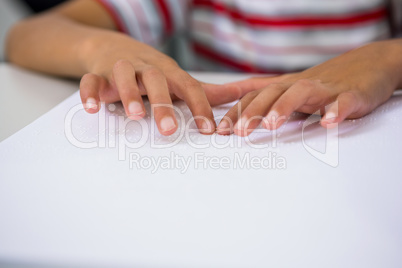 Child reading braille book in classroom