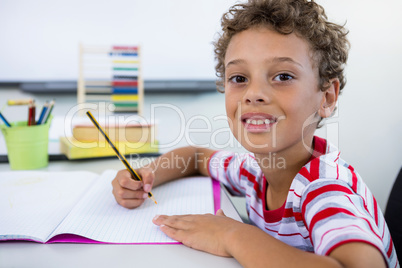 Smiling boy studying at desk in in classroom