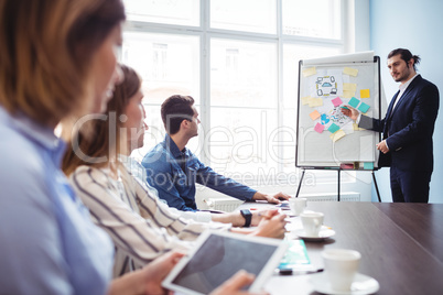 Coworkers looking at businessman giving presentation