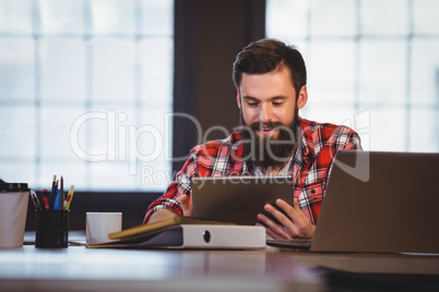 Hipster using digital tablet at desk