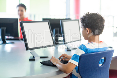 Boy using computer against female teacher