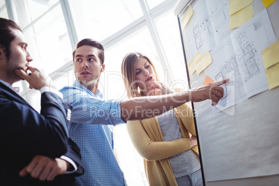 Businessman explaining on blueprints to coworkers