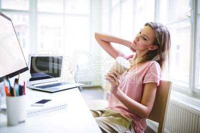 female graphic designer holding disposable coffee cup at desk