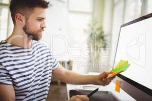 Businessman holding adhesive notes in creative office