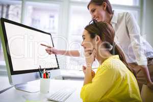 Happy businesswoman pointing at computer screen to colleague at