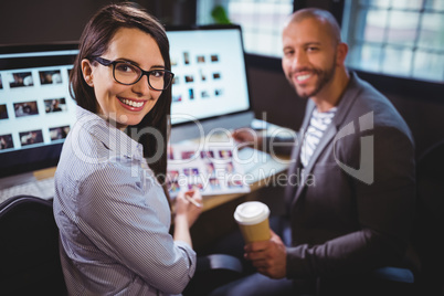 Happy colleagues sitting at computer desk in creative office