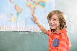 Happy boy pointing on map in classroom