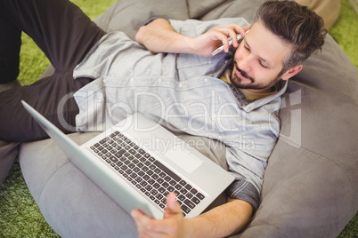 High angle view of businessman using laptop and mobile phone at