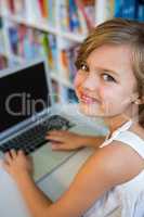 Smiling girl using laptop in school library