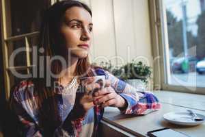 Young thoughtful woman having coffee at cafe