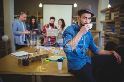 Stylish businessman drinking coffee while sitting at table