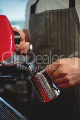 Midsection of barista pouring coffee from espresso maker at cafe
