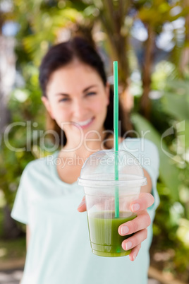Portrait of cheerful woman showing juice