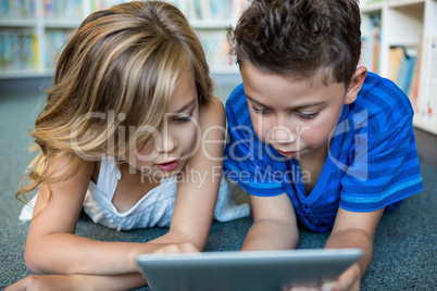 Close-up of girl and boy using digital tablet in library