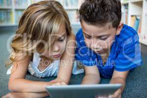 Close-up of girl and boy using digital tablet in library