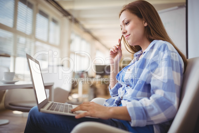 Businesswoman working on laptop in creative office