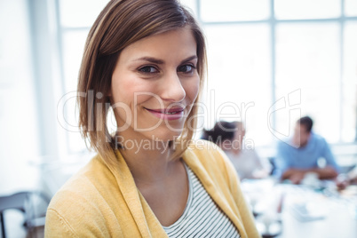 Smiling businesswoman standing against colleagues