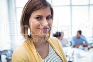 Smiling businesswoman standing against colleagues