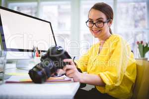 Portrait of confident photographer with camera at creative offic