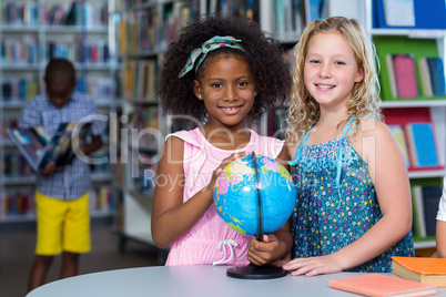 Smiling girls with globe on table