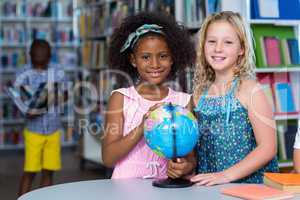Smiling girls with globe on table