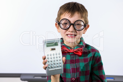 Smiling boy holding calculator in classroom