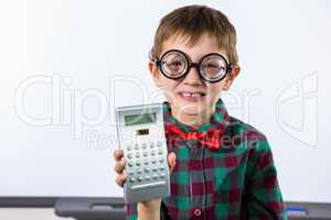 Smiling boy holding calculator in classroom