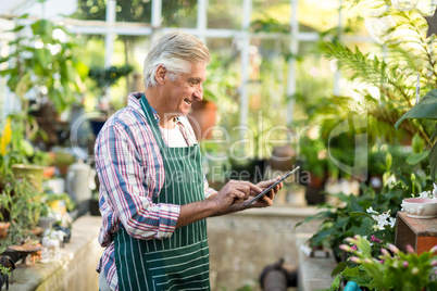 Mature man using digital tablet at greenhouse