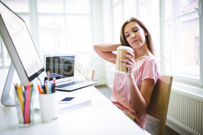 Tired attractive graphic designer holding disposable coffee cup