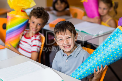 Cheerful boy with classmates holding craft item