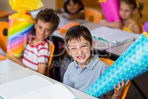 Cheerful boy with classmates holding craft item