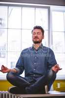 Executive meditating in lotus position at creative office