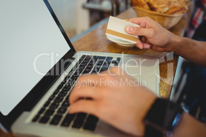 Close-up of customer spending money on online at cafe