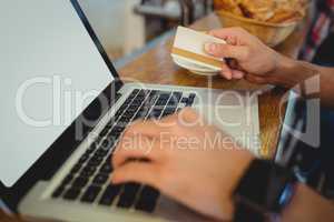 Close-up of customer spending money on online at cafe