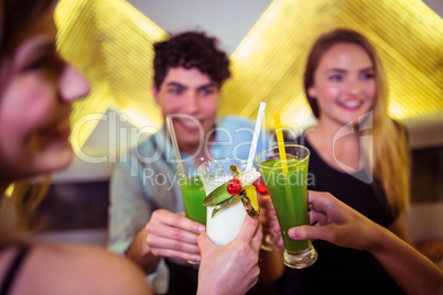 Smiling friends toasting cocktail