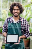 Male gardener showing digital tablet at greenhouse