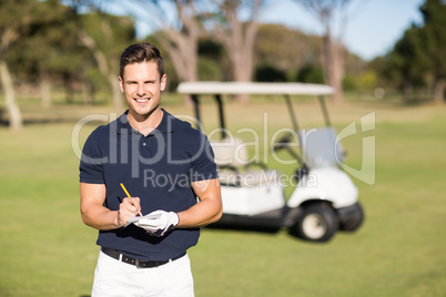 Portrait of smiling golfer writing on score card