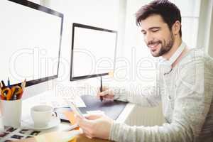 Smiling businessman using graphics tablet at desk