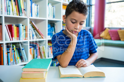Elementary boy reading book in school library