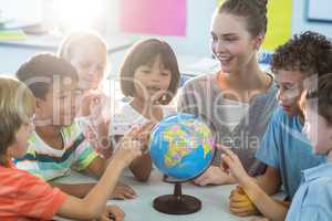 Female teacher showing globe to children