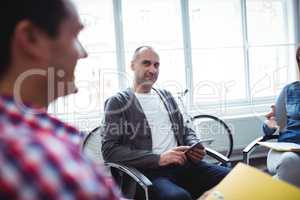 Businessman looking at coworker while using digital tablet