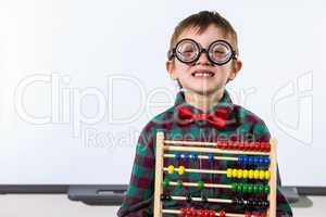 Cute boy with abacus against whiteboard in classroom