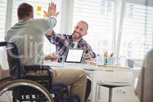 Handicap businessman giving high-five to colleague in office