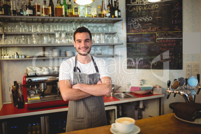 Portrait of confident barista with arms crossed at coffee house