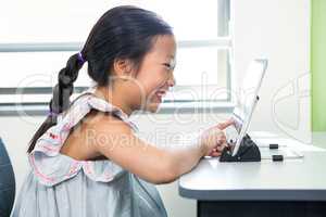Smiling girl using laptop in classroom