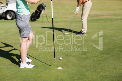 Low section of couple playing golf